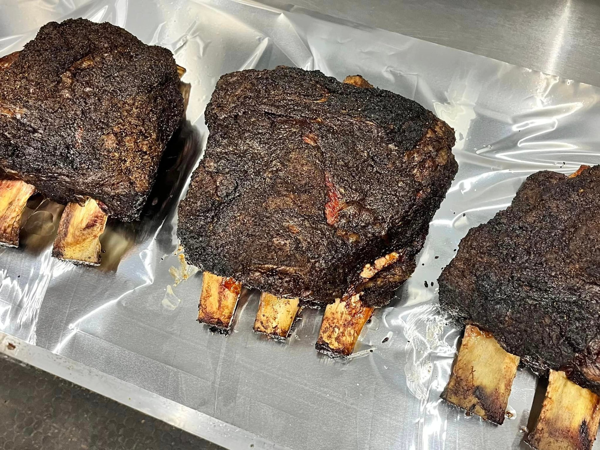 Multiple beef short ribs with dark bark on white butcher paper